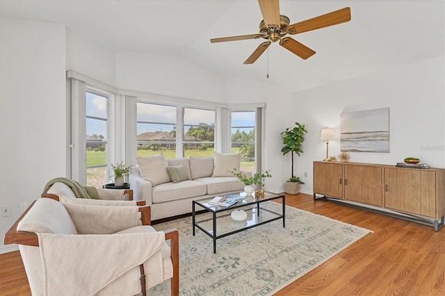 living room with light wood-type flooring, vaulted ceiling, a wealth of natural light, and ceiling fan