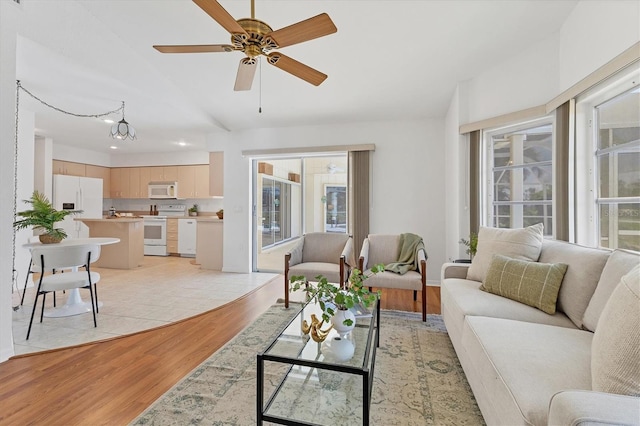 living room featuring ceiling fan with notable chandelier and light wood-type flooring