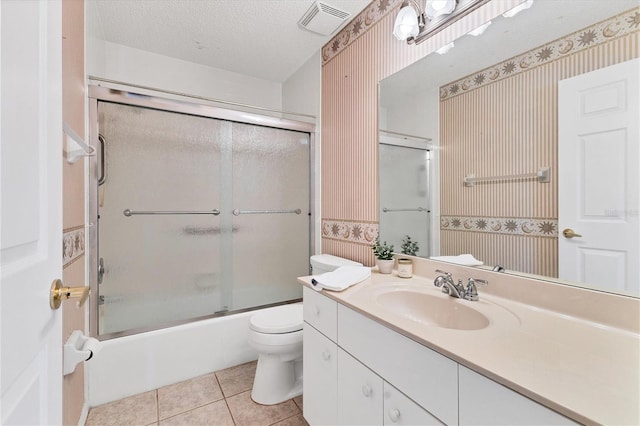 full bathroom with combined bath / shower with glass door, vanity, a textured ceiling, tile patterned flooring, and toilet