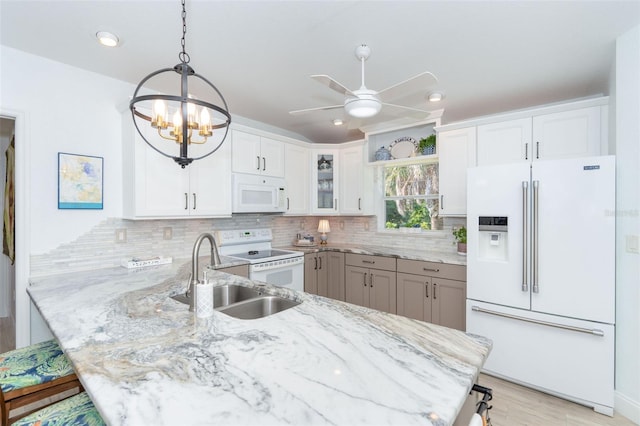 kitchen with white cabinets, light stone counters, white appliances, and kitchen peninsula