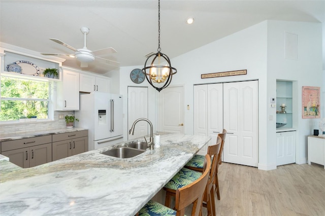 kitchen with lofted ceiling, sink, hanging light fixtures, high end white fridge, and white cabinetry