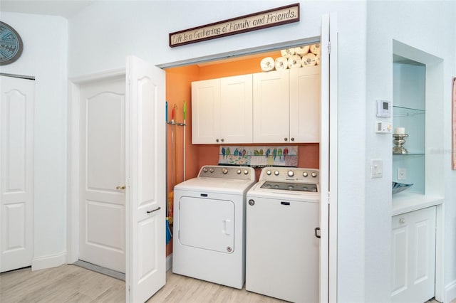 laundry room with cabinets, light wood-type flooring, and washer and clothes dryer