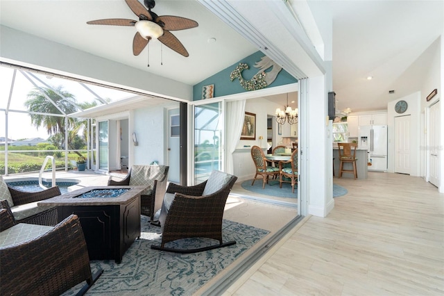 interior space with ceiling fan with notable chandelier, lofted ceiling, and light hardwood / wood-style flooring