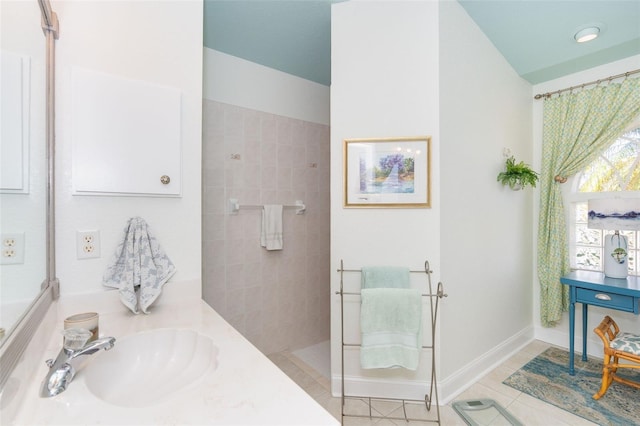 bathroom with tile patterned flooring, vanity, and tiled shower