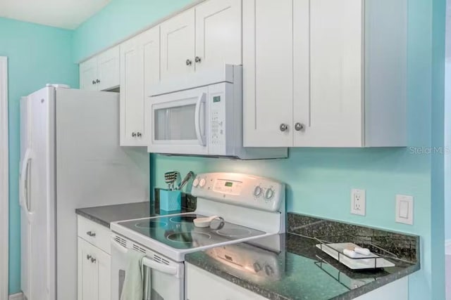 kitchen featuring white cabinets, white appliances, and dark stone counters