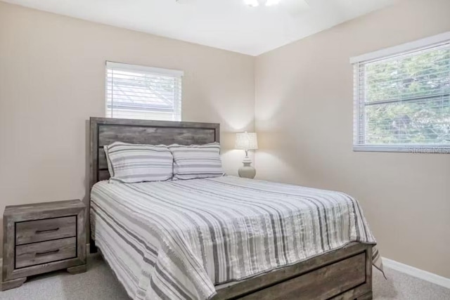 bedroom featuring multiple windows, ceiling fan, and light colored carpet