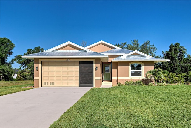 ranch-style house with driveway, metal roof, a front lawn, and stucco siding