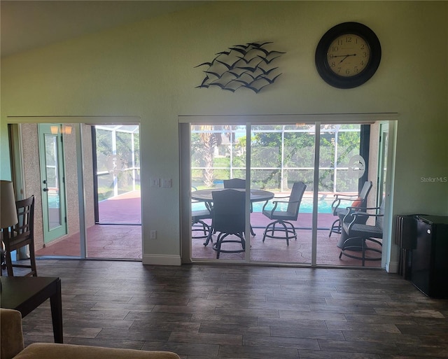 interior space with high vaulted ceiling, dark wood-style flooring, plenty of natural light, and baseboards