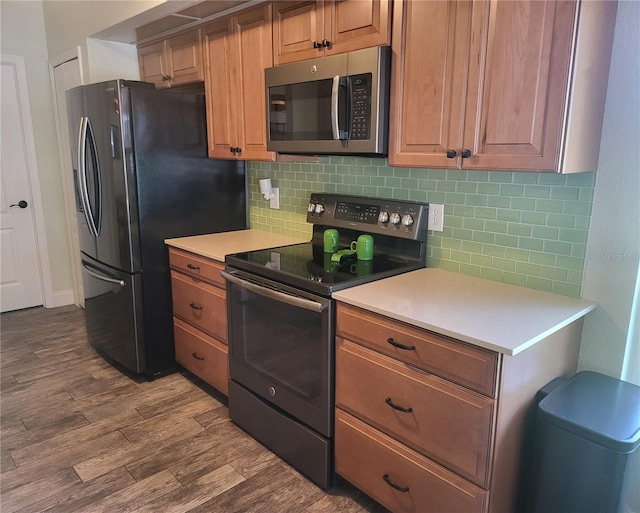 kitchen with dark wood-style floors, light countertops, appliances with stainless steel finishes, and decorative backsplash