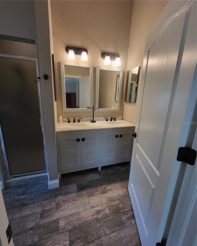 bathroom featuring walk in shower, dual bowl vanity, and hardwood / wood-style floors