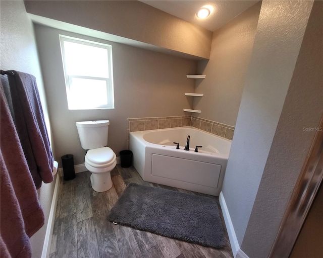 bathroom with a bathing tub, hardwood / wood-style flooring, and toilet