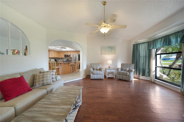 living room with dark wood-type flooring, ceiling fan, and vaulted ceiling