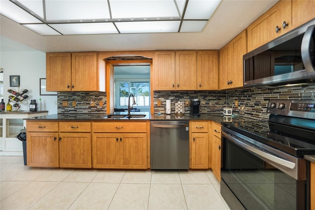 kitchen featuring sink, decorative backsplash, light tile patterned flooring, and appliances with stainless steel finishes