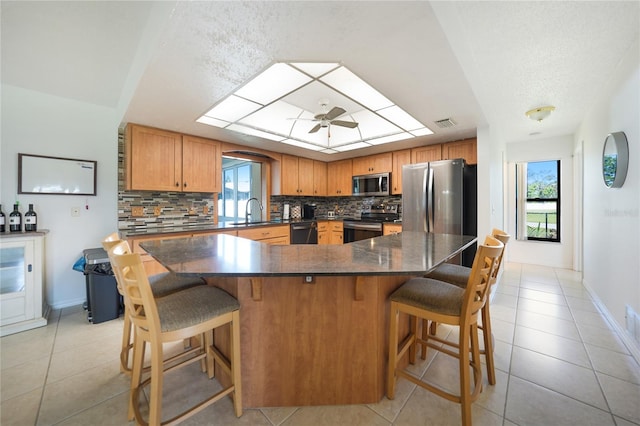 kitchen featuring stainless steel appliances, tasteful backsplash, light tile patterned floors, and a skylight