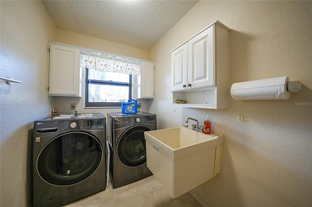 clothes washing area with sink, light tile patterned floors, cabinets, washer and dryer, and a textured ceiling