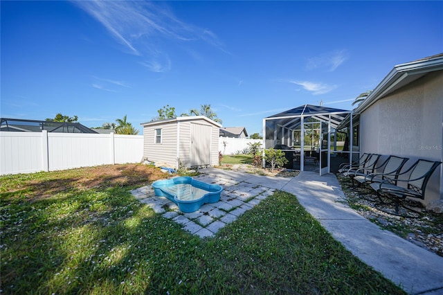 view of yard featuring a shed, a patio, and glass enclosure