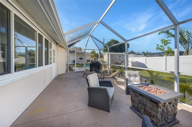 view of patio with a storage shed, glass enclosure, and an outdoor fire pit