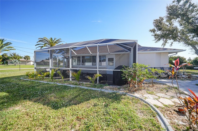 back of house with a yard and a lanai