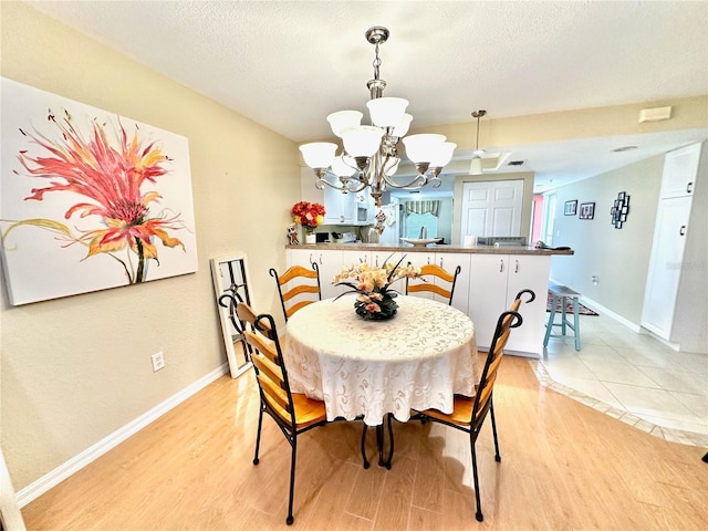 dining room with an inviting chandelier, a textured ceiling, and light wood-type flooring