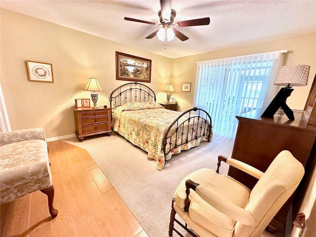 bedroom featuring ceiling fan, hardwood / wood-style flooring, access to outside, and a textured ceiling