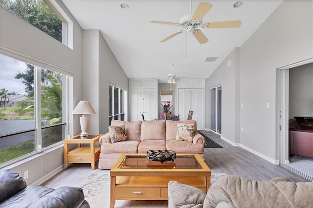 living room with ceiling fan, high vaulted ceiling, and light wood-type flooring