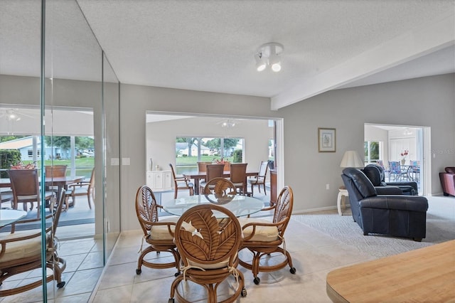 dining area featuring beam ceiling, light tile patterned flooring, and a textured ceiling