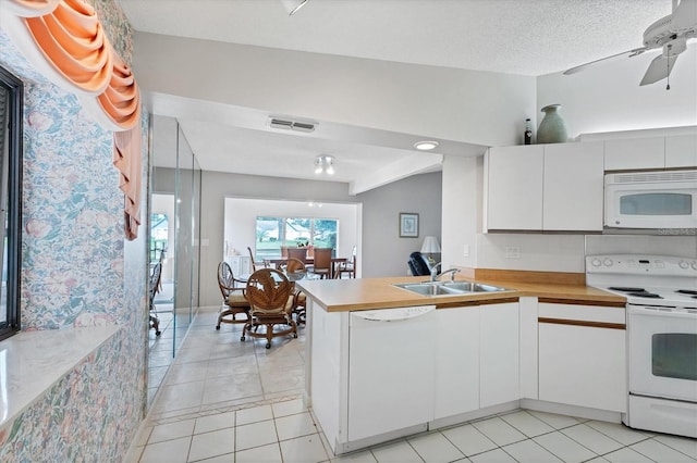 kitchen with kitchen peninsula, a textured ceiling, white appliances, sink, and white cabinets