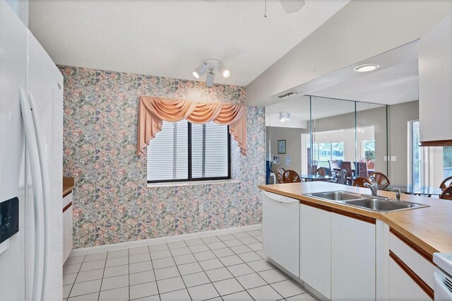 kitchen with white appliances, sink, light tile patterned floors, decorative light fixtures, and white cabinets