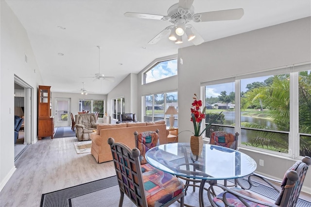 dining room with a water view, high vaulted ceiling, ceiling fan, and light hardwood / wood-style floors