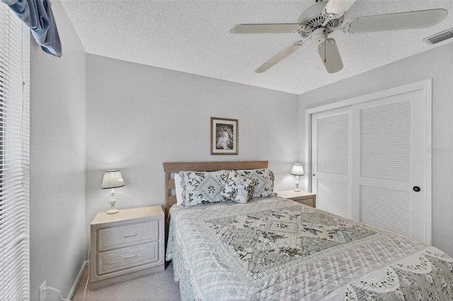 carpeted bedroom with a textured ceiling, a closet, and ceiling fan