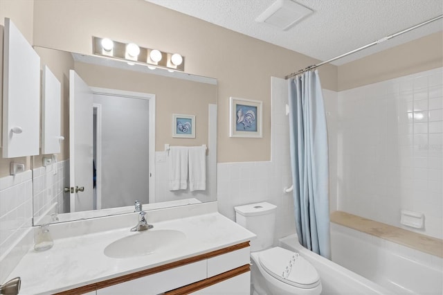 full bathroom featuring shower / tub combo, vanity, a textured ceiling, tile walls, and toilet