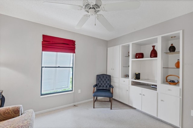 living area with built in shelves, a textured ceiling, light colored carpet, and ceiling fan