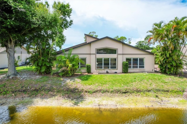 back of property featuring a water view and a yard