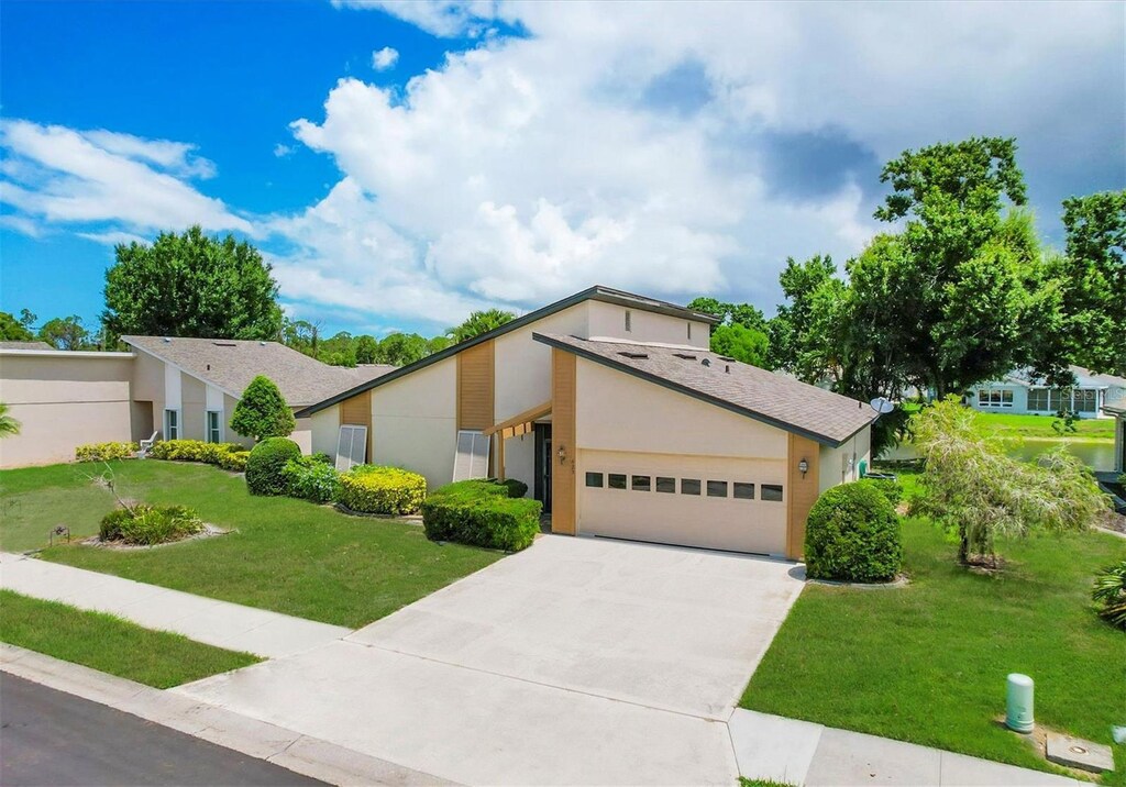 425 Cypress Forest Dr, Englewood, FL 34223 - mid-century inspired home featuring a front yard, an attached garage, driveway, and stucco siding