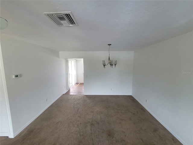 carpeted empty room with a notable chandelier