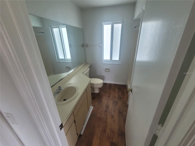 bathroom featuring vanity with extensive cabinet space, hardwood / wood-style flooring, and toilet