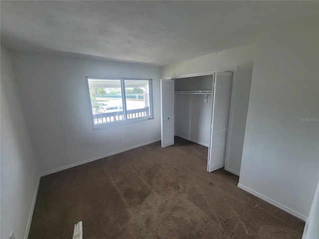 unfurnished bedroom featuring a closet and dark colored carpet