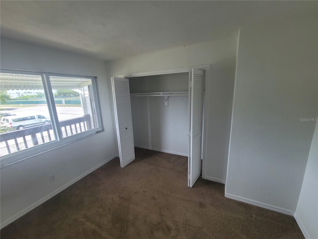 unfurnished bedroom with dark colored carpet and a closet