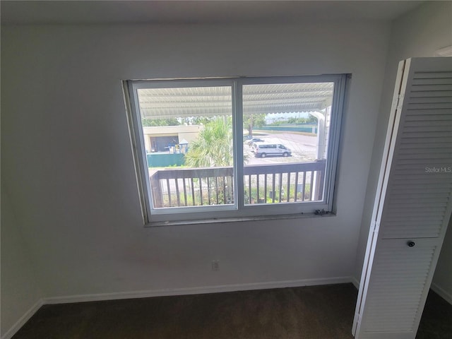 unfurnished bedroom featuring a closet, dark colored carpet, and multiple windows