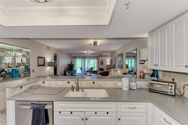 kitchen with kitchen peninsula, backsplash, stainless steel dishwasher, sink, and white cabinets