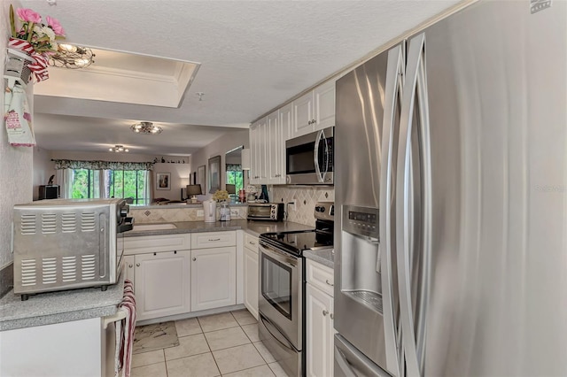 kitchen with white cabinets, light tile patterned flooring, stainless steel appliances, and a textured ceiling