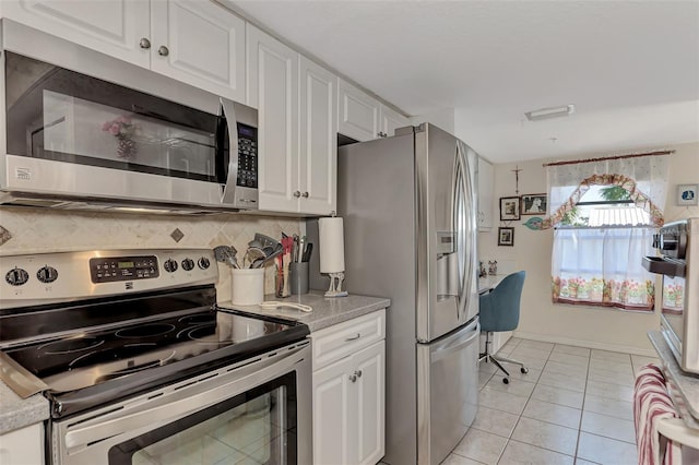 kitchen featuring backsplash, white cabinets, stainless steel appliances, and light tile patterned floors