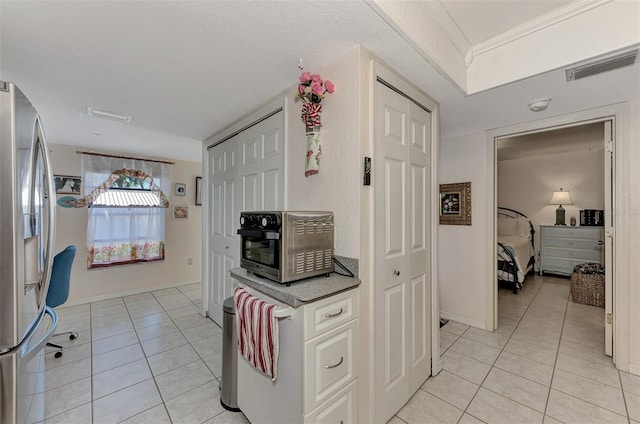 kitchen with stainless steel fridge with ice dispenser, white cabinetry, and light tile patterned floors