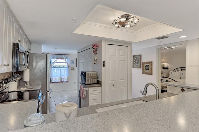 kitchen with stainless steel appliances, a raised ceiling, crown molding, sink, and white cabinetry