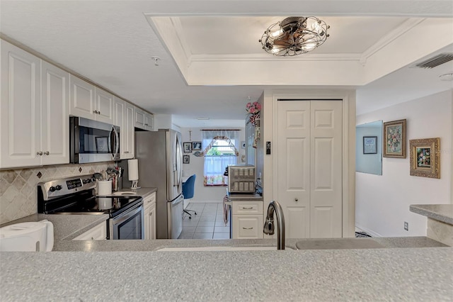 kitchen featuring tasteful backsplash, stainless steel appliances, crown molding, white cabinetry, and light tile patterned flooring