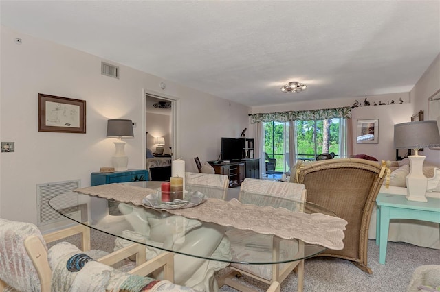 carpeted dining area with a textured ceiling