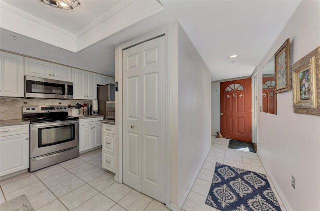 kitchen featuring light tile patterned floors, tasteful backsplash, appliances with stainless steel finishes, white cabinets, and ornamental molding