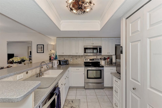 kitchen featuring white cabinetry, sink, kitchen peninsula, crown molding, and appliances with stainless steel finishes