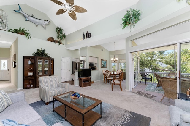 living room with carpet flooring, high vaulted ceiling, and ceiling fan with notable chandelier