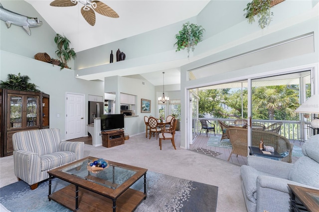 carpeted living room featuring ceiling fan with notable chandelier and high vaulted ceiling